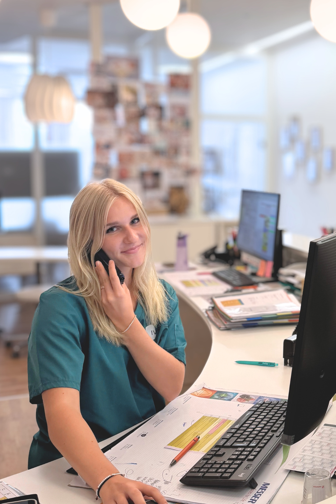 Katharina Rothbauer vom IVY Zentrum für Kinderwunsch telefonierend am Arbeitsplatz im Empfangsbereich der IVY Kinderwunschklinik
